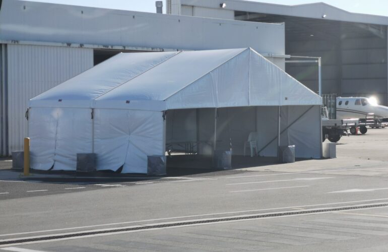 A white 10x10m event tent set up outdoors on a paved surface.