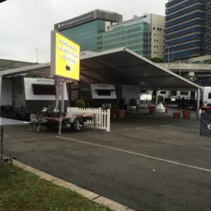 An open-sided tent covering a few trailers, with a sign that says "WORD HUNT COMPETITION LOCATION."
