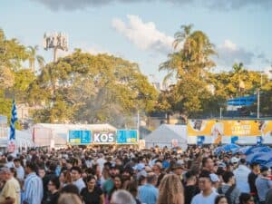 crowd of people with stalls and trees in background